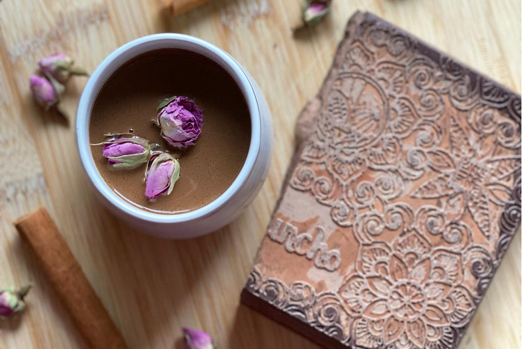 Tasse Kakao mit Rosenblüten auf einem Holztisch
